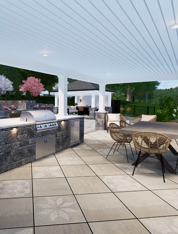 Outdoor covered patio featuring a built-in grill and kitchen area, wicker chairs with a small table, and tiled flooring with decorative patterns. Trees and a fenced yard are visible in the background.