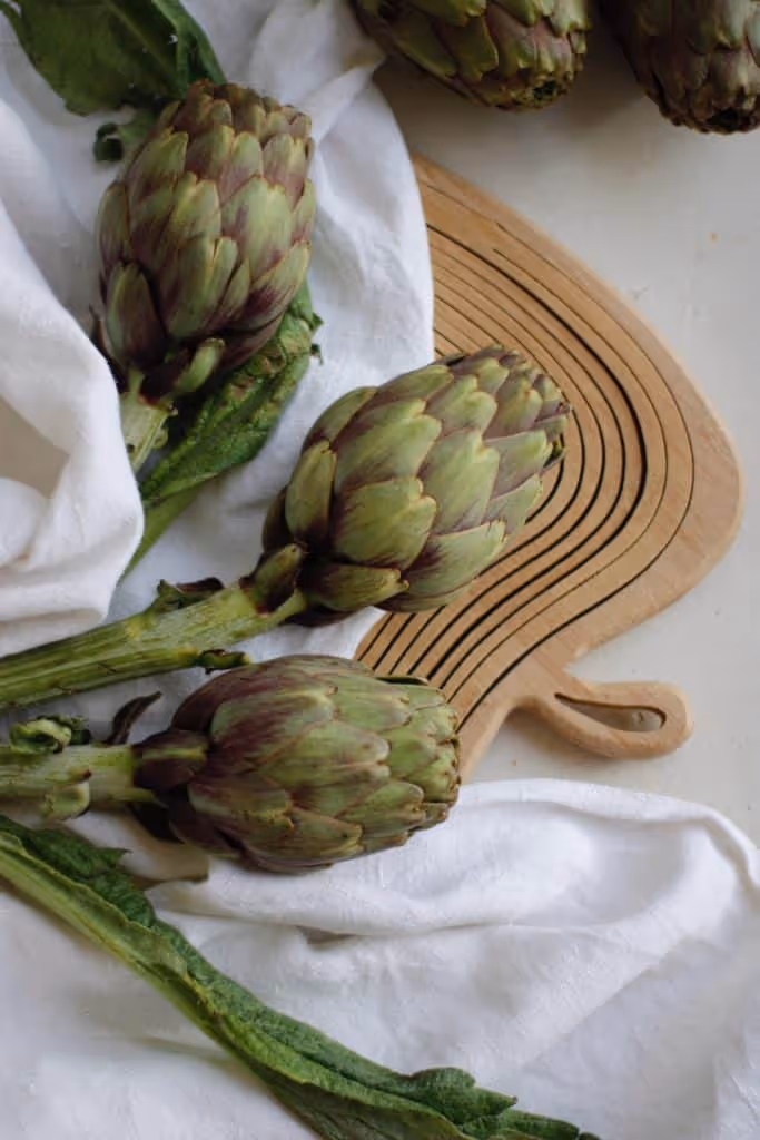 Artichokes and asparagus on a wood cutting board