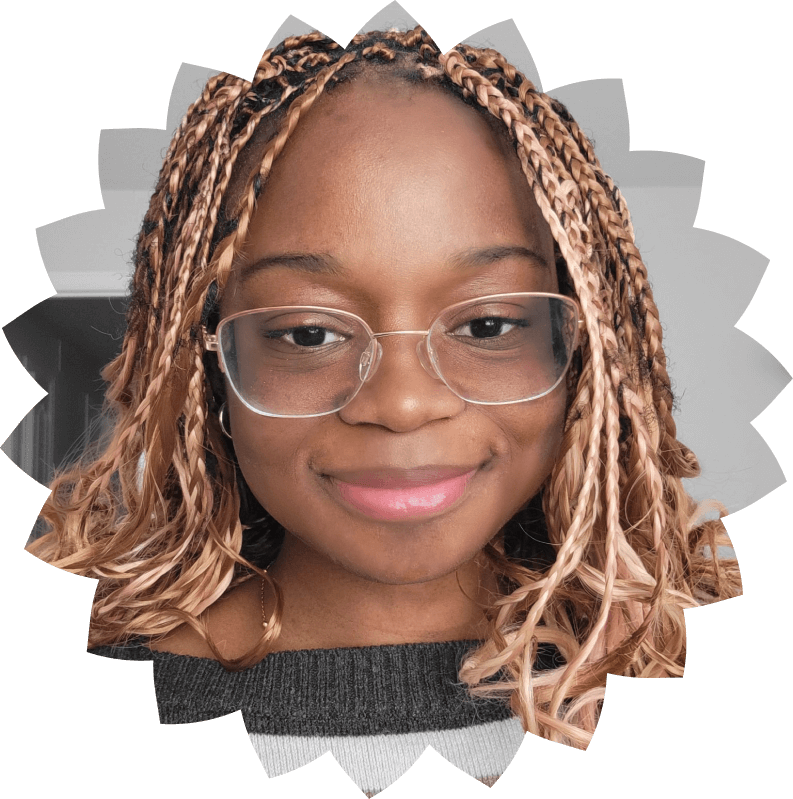 Close-up portrait of a smiling young woman with braided pink and brown hair wearing glasses and a dark sweater.
