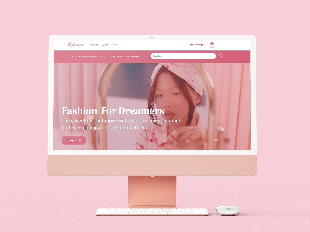 Rose gold iMac displaying a fashion website with a woman looking into a mirror and text 'Fashion For Dreamers' on a pink background, accompanied by a keyboard and mouse.