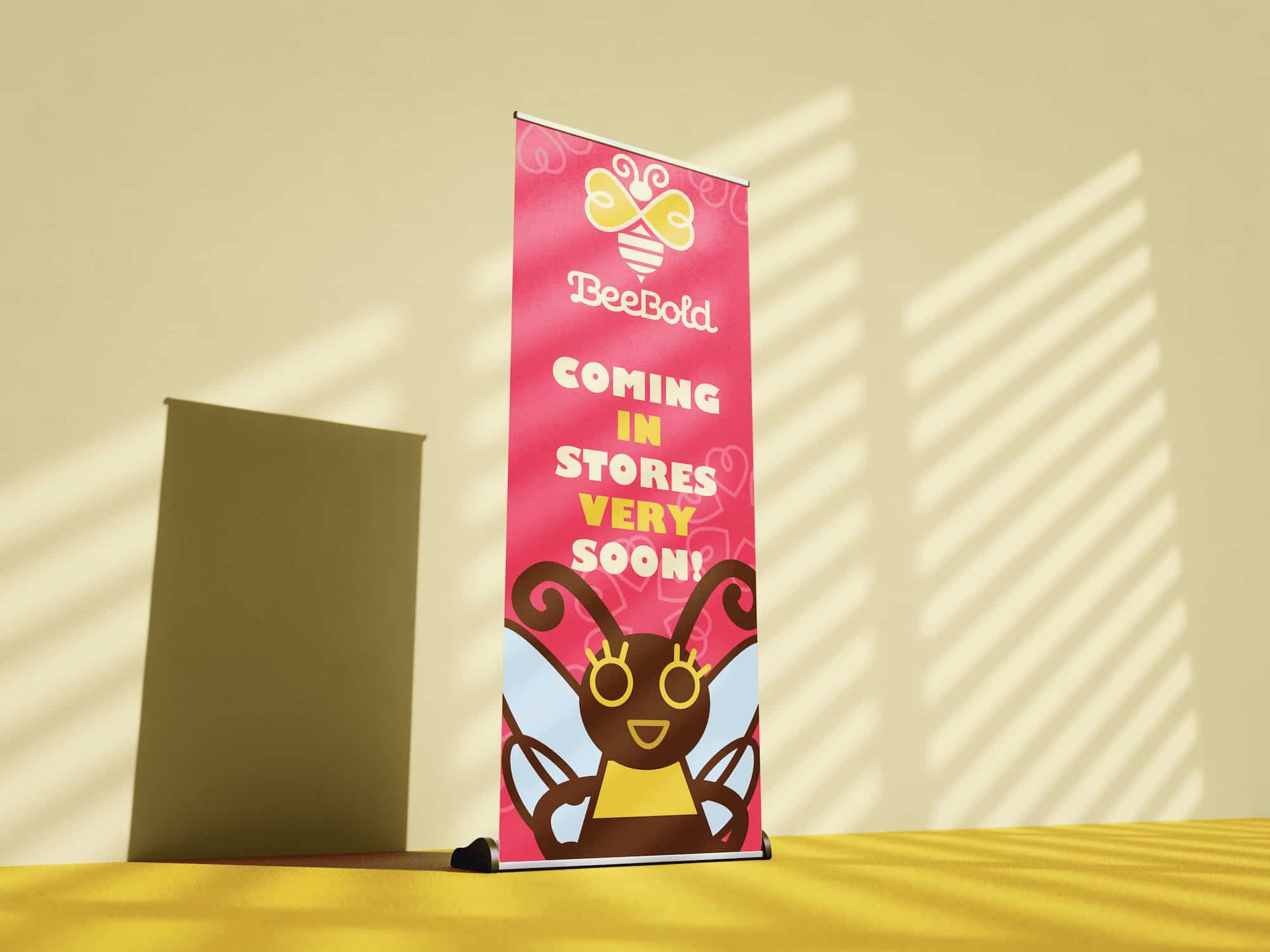 Pink promotional banner with BeeBold logo and cartoon bee, text reads 'Coming in stores very soon!'