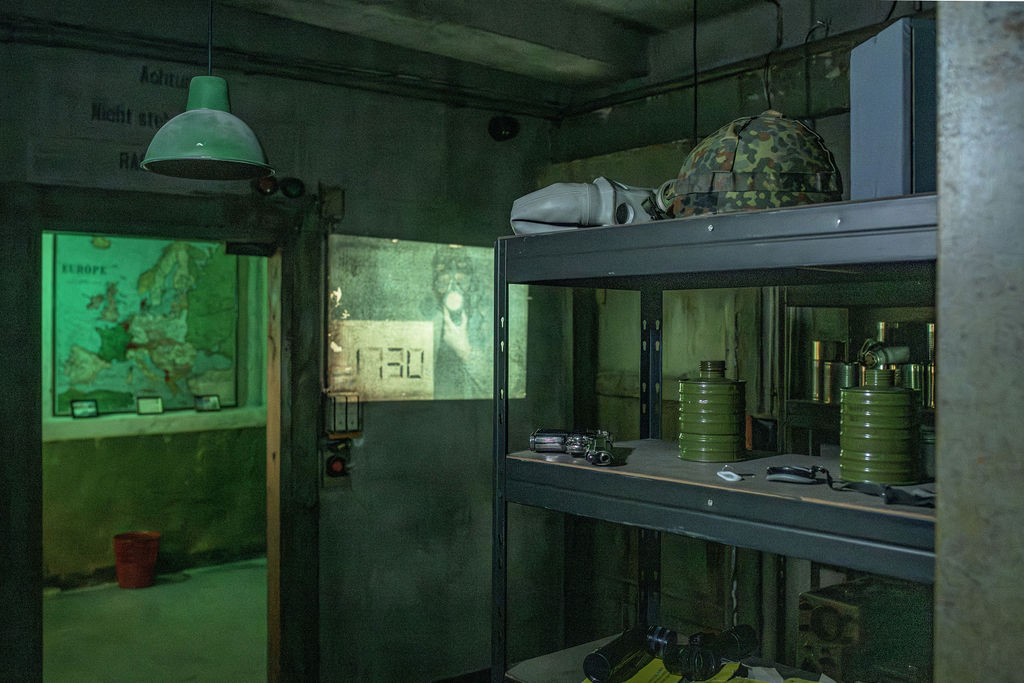 Ein Schwerlastregal mit alten Weltkriegssachen darin. Ein angeschalteter Diaprojektor.