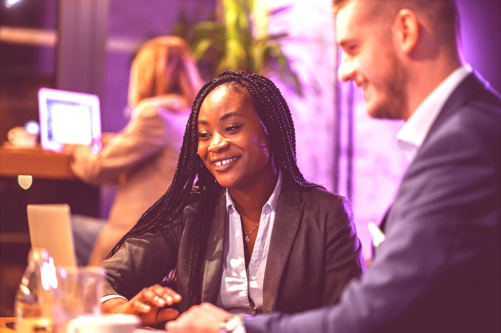 Event planning team meeting with a smiling client in a vibrant pink workspace.