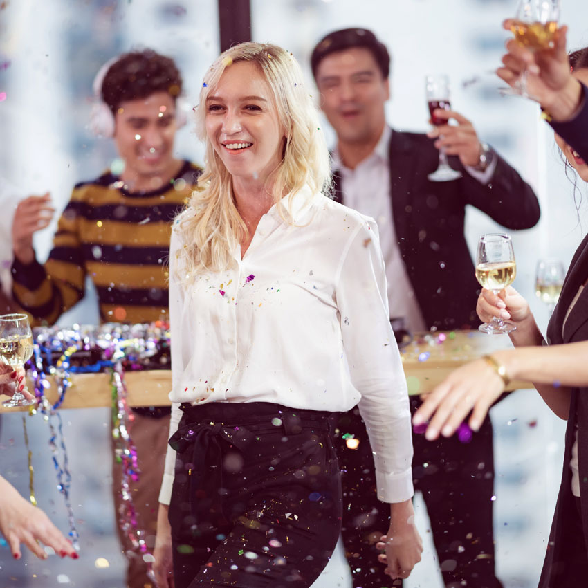 Guests gathered around, celebrating with confetti and drinks at an exciting planned event. 