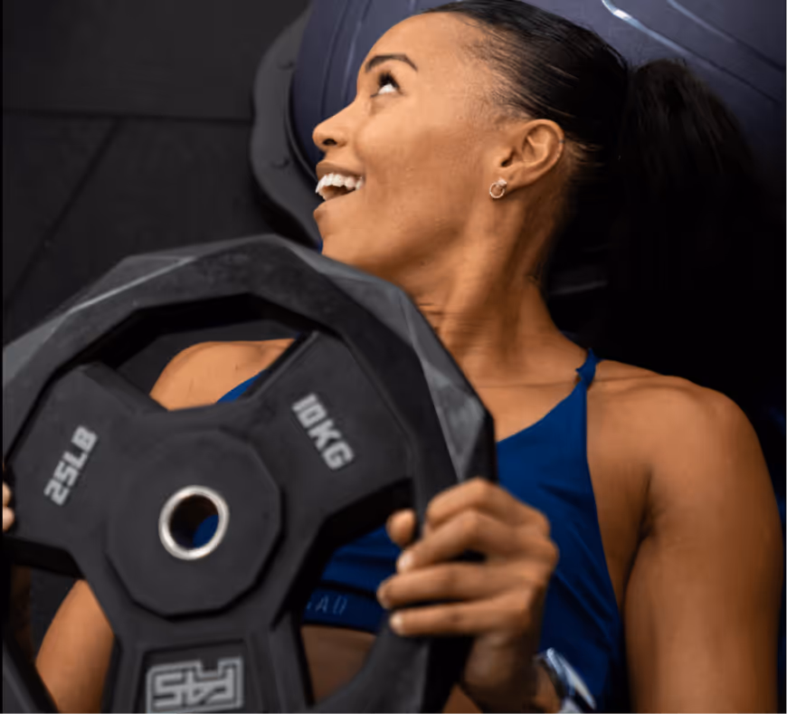 Woman holding a 10kg plate exercising in an F45 class