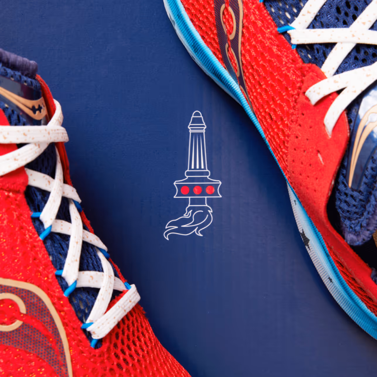 Close-up of red and navy blue athletic shoes with white laces on a blue background featuring a white sword with red dots and flames graphic.