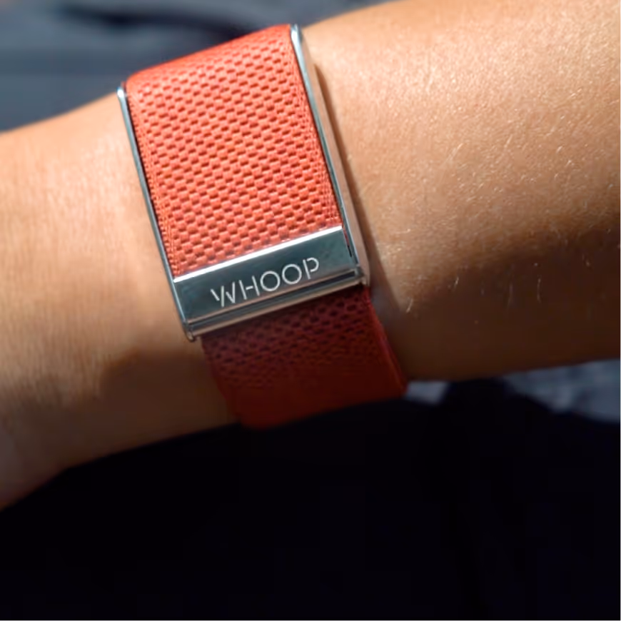 Close-up of a wrist wearing a red WHOOP fitness tracker band.