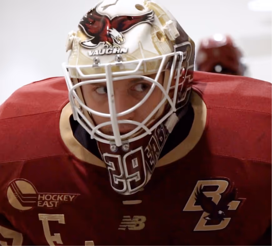 Ice hockey goalie wearing a maroon and gold Boston College uniform and helmet with a red eagle design.