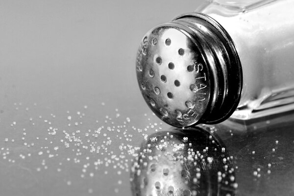 Salt spilt on table with salt shaker