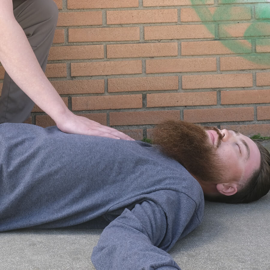 Man passed out on sidewalk, another hand reaching in to frame