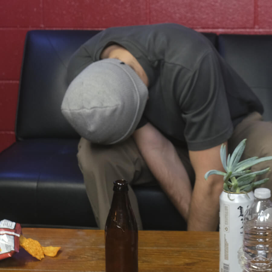 Man in beanie passed out on couch, leaning forward