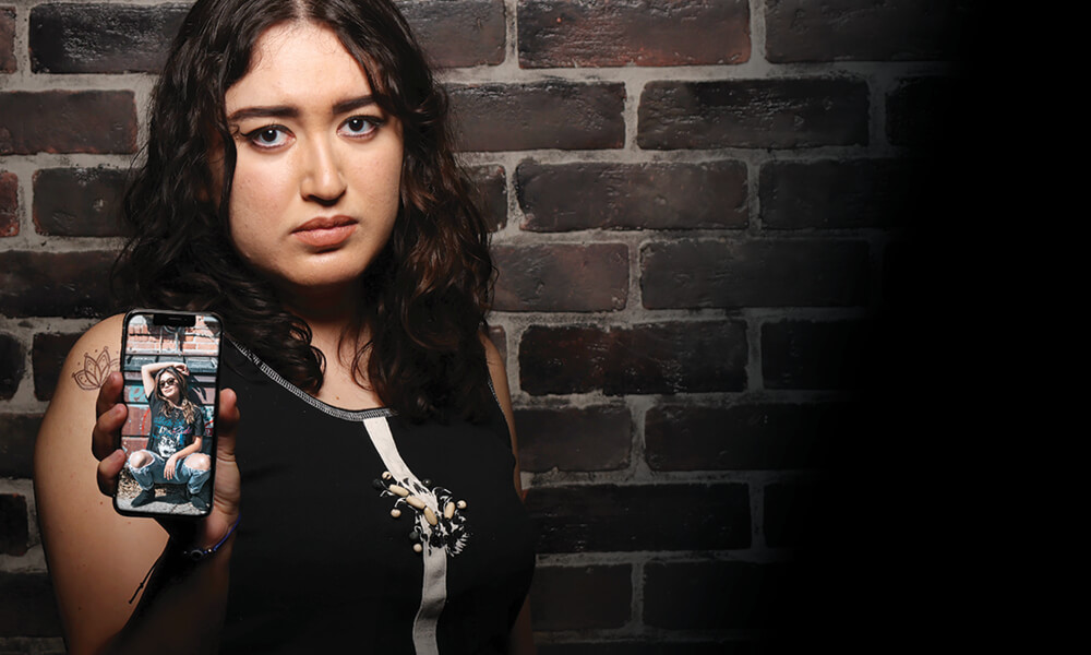 Young woman showing phone with photo of her friend