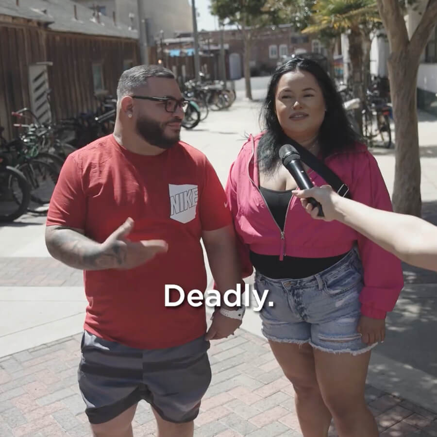Man and woman standing on street talking to person with microphone
