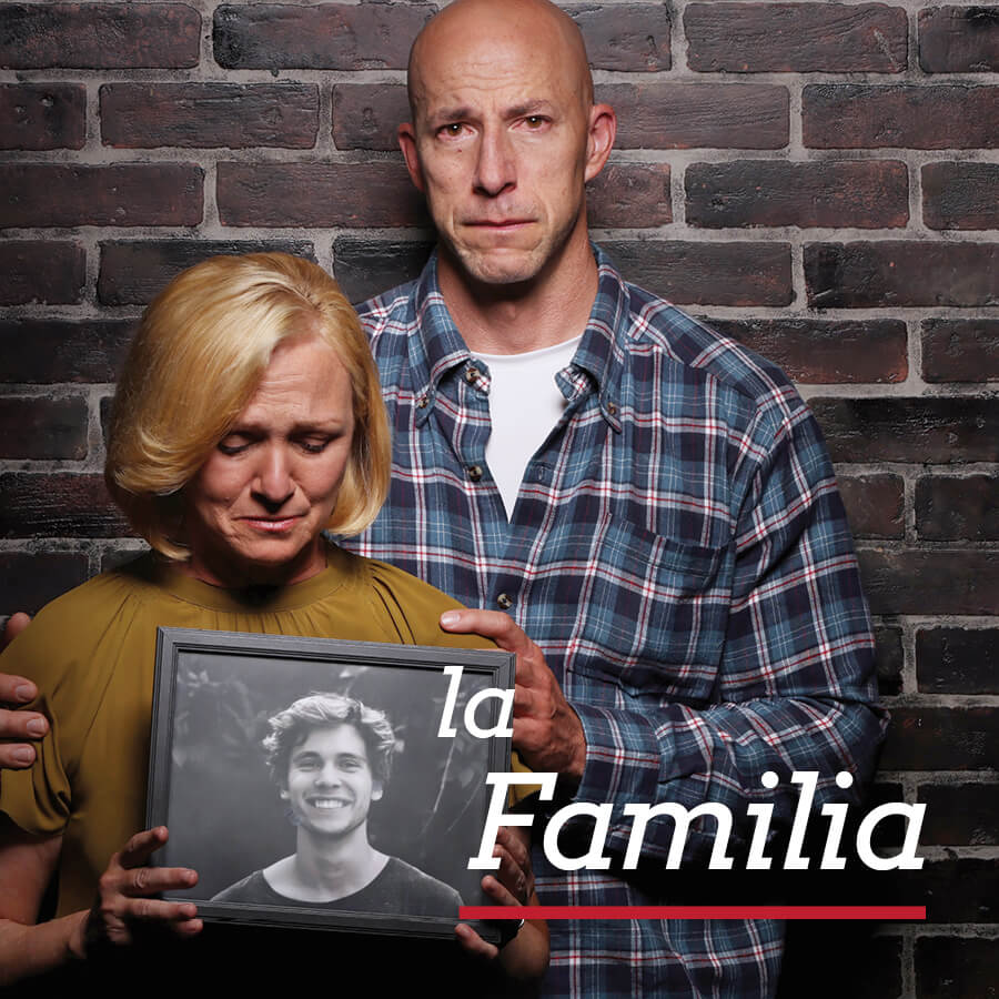 Una madre y un padre sosteniendo una foto de su hijo, con rostro triste