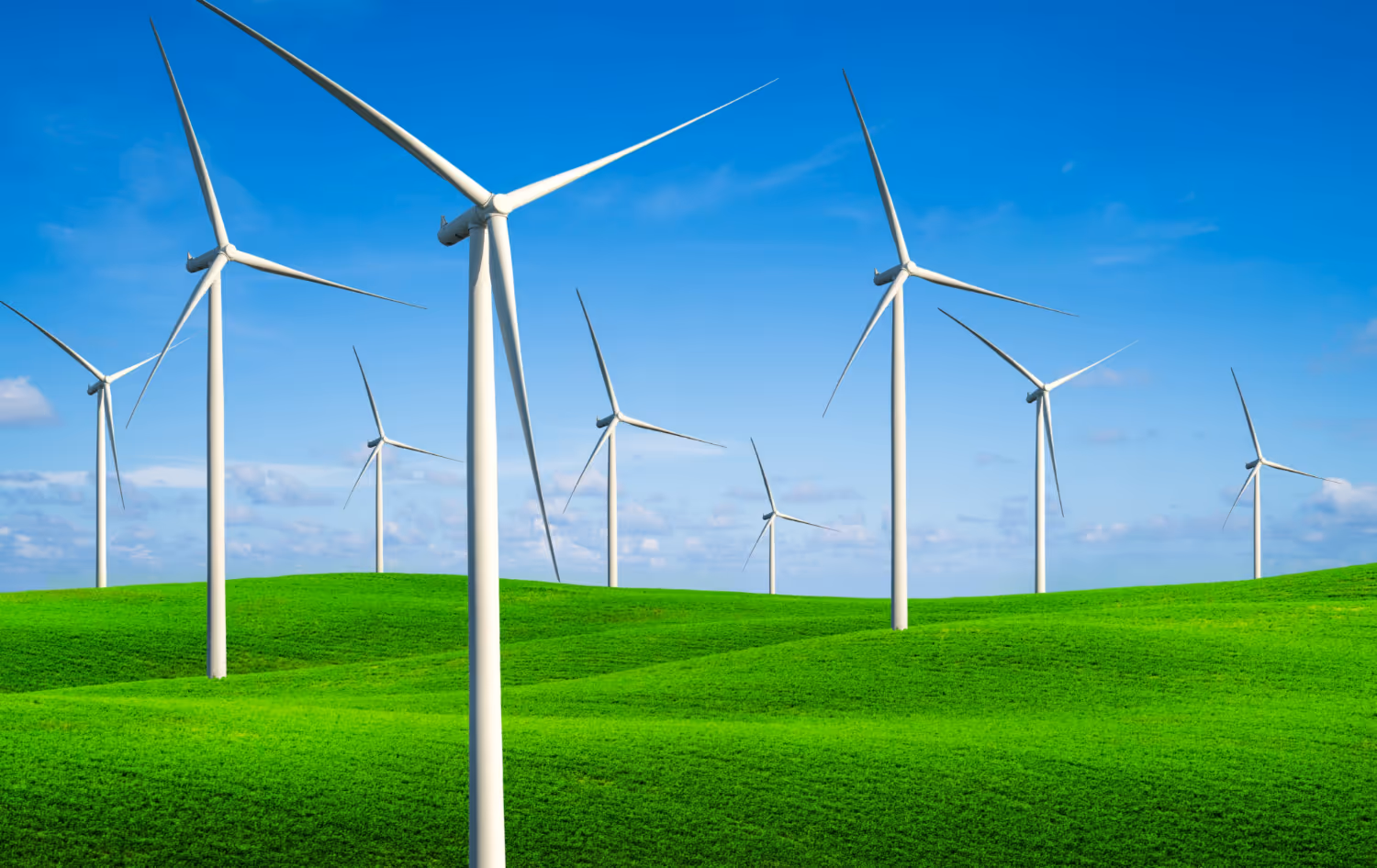 Wind turbines on rolling green hills under a clear blue sky.