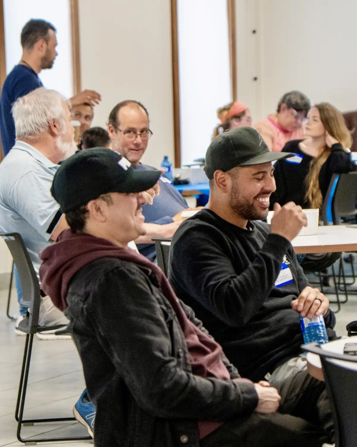 Group of people chatting and laughing indoors at a casual meeting or workshop.