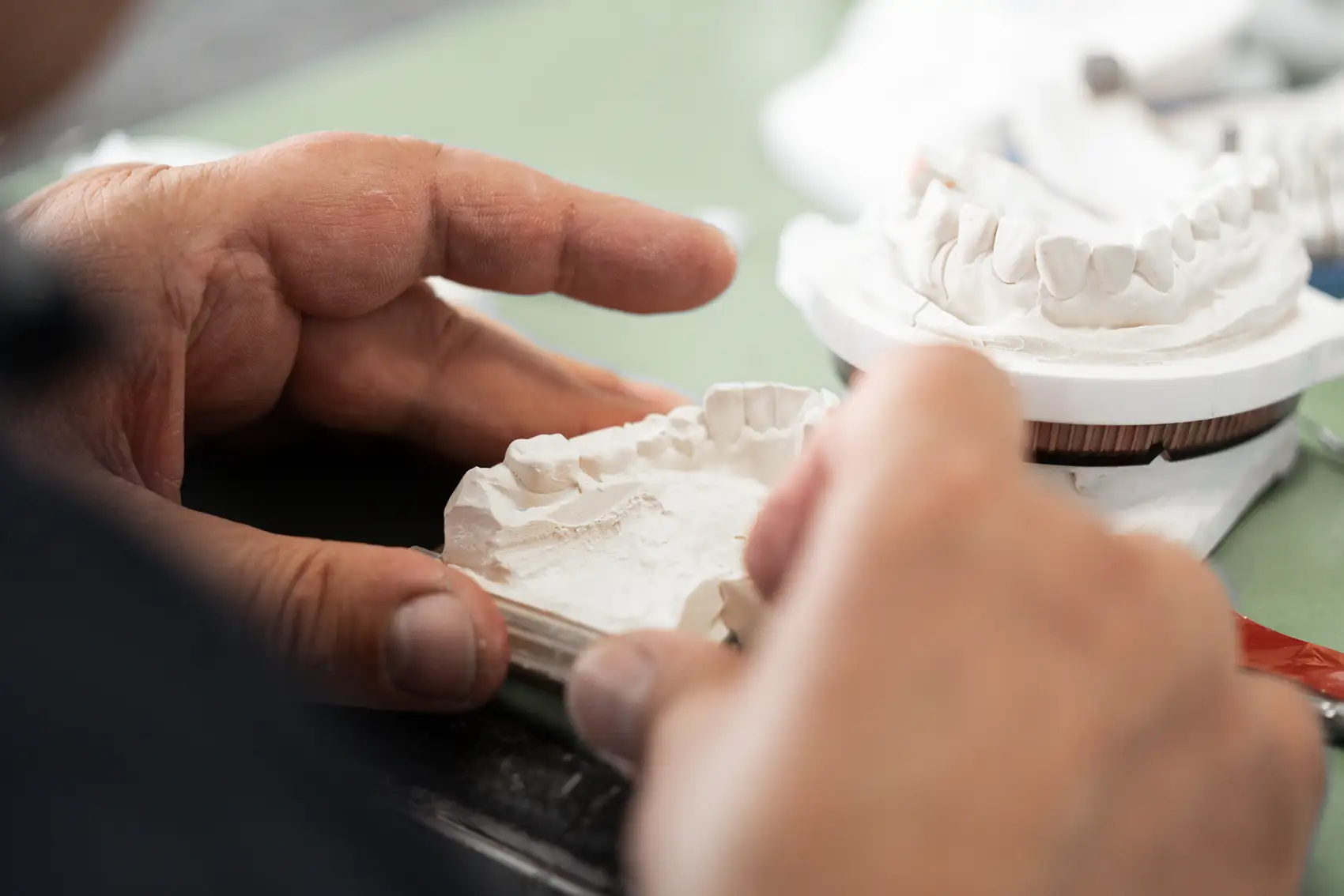 Hände arbeiten an Zahprotese