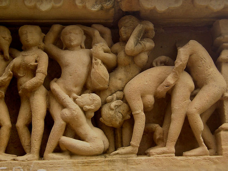 Ancient stone carving depicting several intertwined human figures engaging various group sex poses.