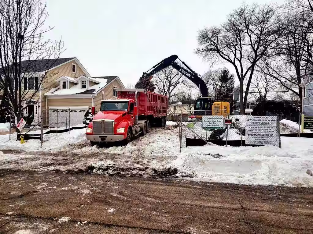 Donegal Services demolishing a home during winter conditions, with excavator and dump truck operating in the snow.