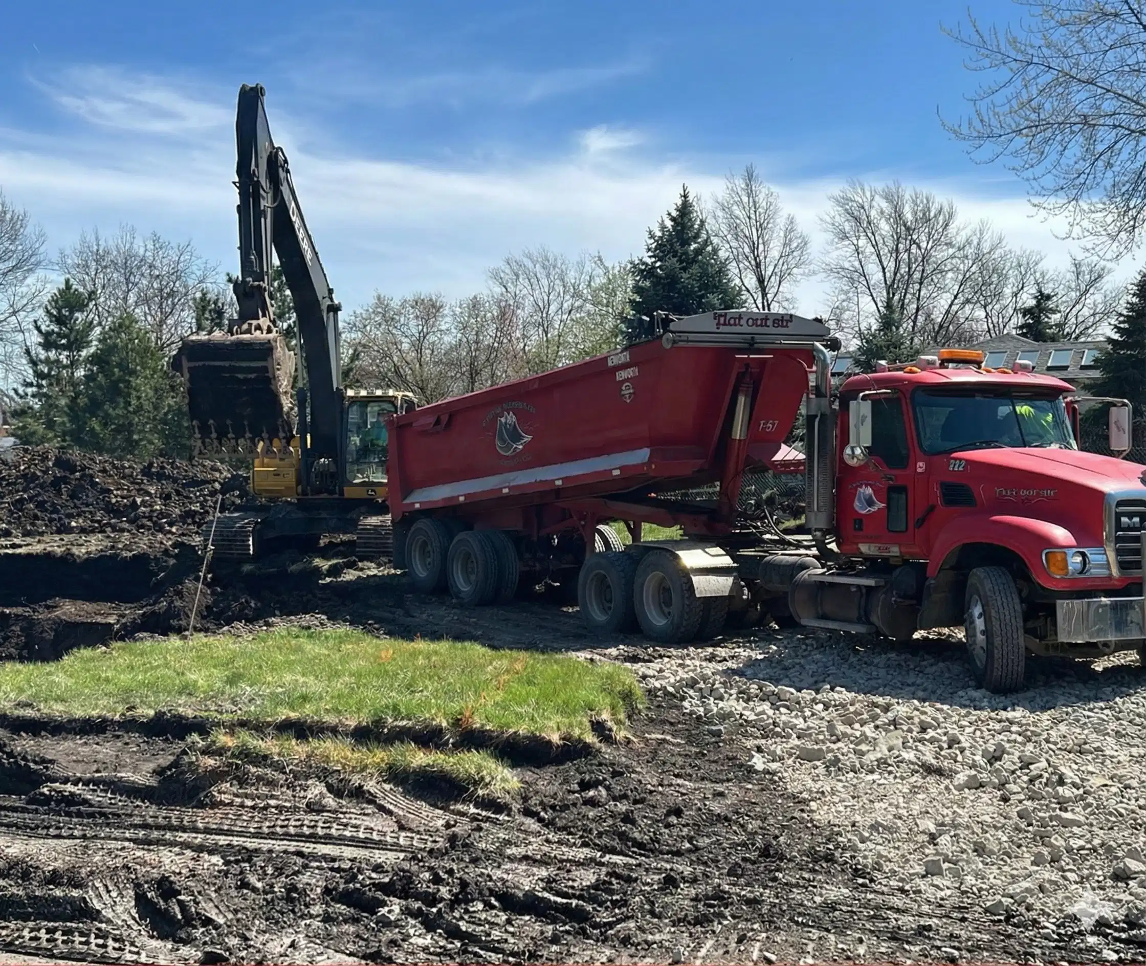 Excavator loading soil into a Donegal Services dump truck during site excavation and hauling work in the Chicagoland area.
