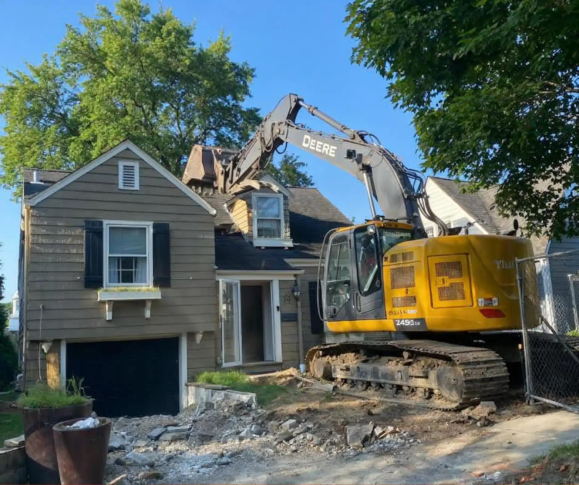 John Deere excavator removing a brick chimney during residential demolition by Donegal Services in Chicagoland.