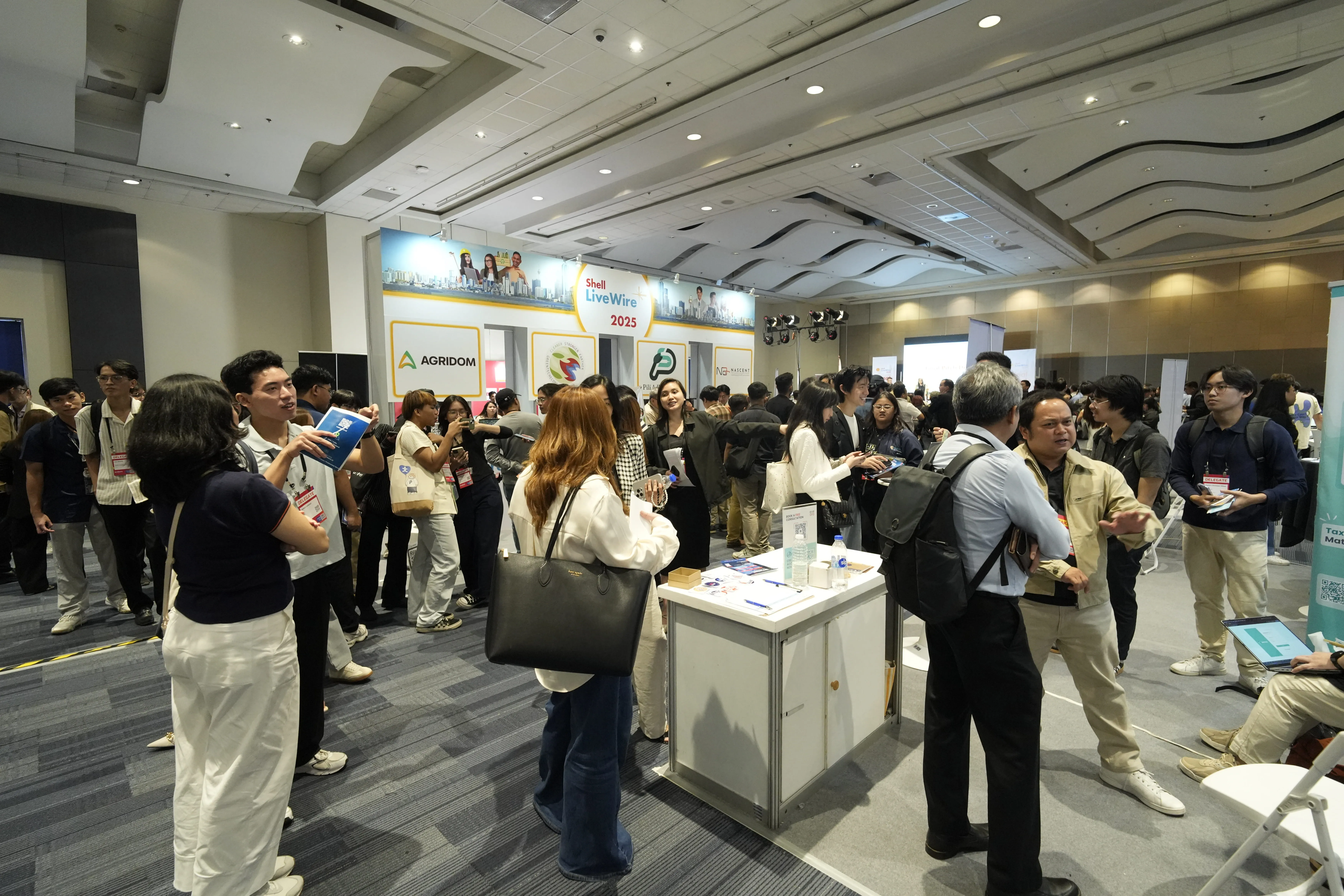 Crowd of people networking and talking at a Shell LiveWire 2025 event inside a convention hall.