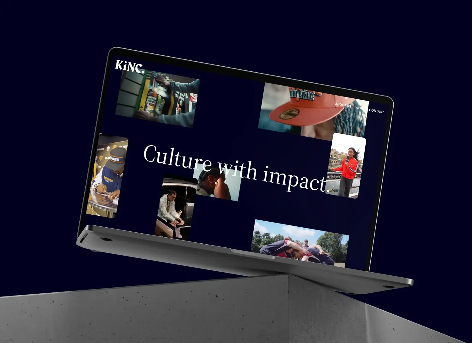 Laptop tilted on a concrete block displaying a website with the text 'Culture with impact.' and various images of people and activities.