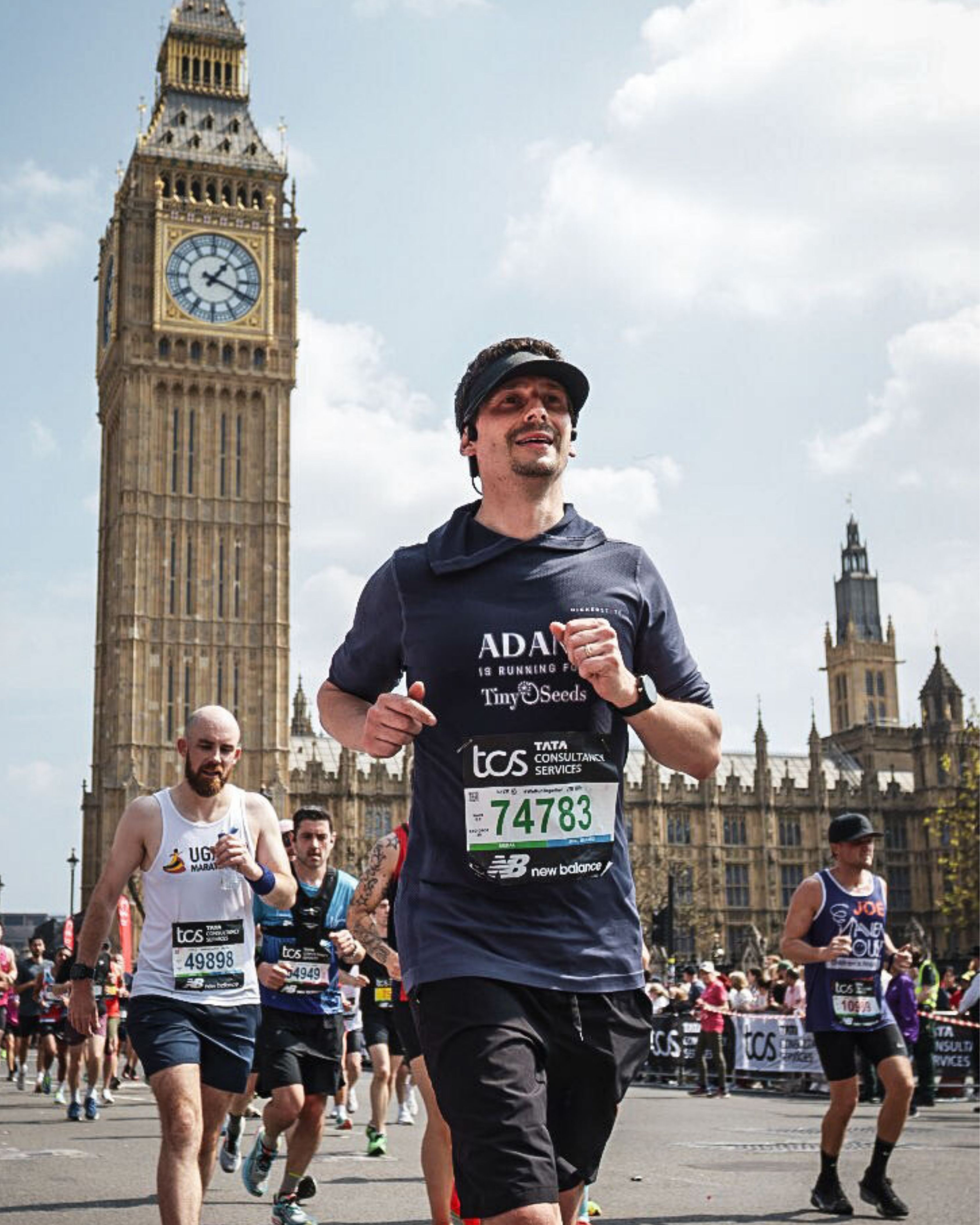 Group of marathon runners passing Big Ben and the Palace of Westminster in London on a sunny day.