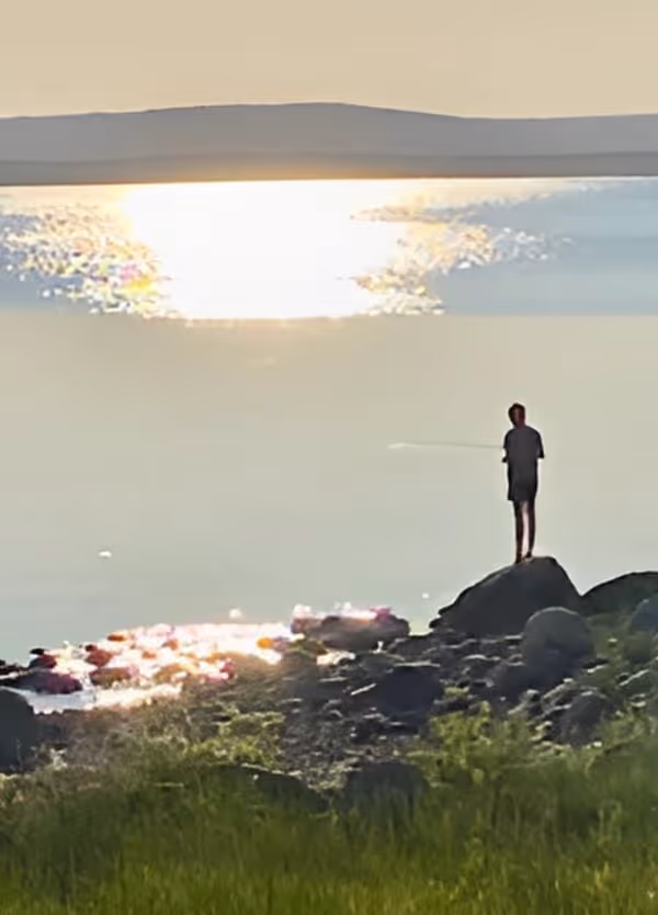 En person står på en klippa vid vattnet i solnedgången, i en lugn och stilla miljö som symboliserar den balans och återhämtning som Vigilans Umeå AB strävar efter att hjälpa personer med ADHD att uppnå.