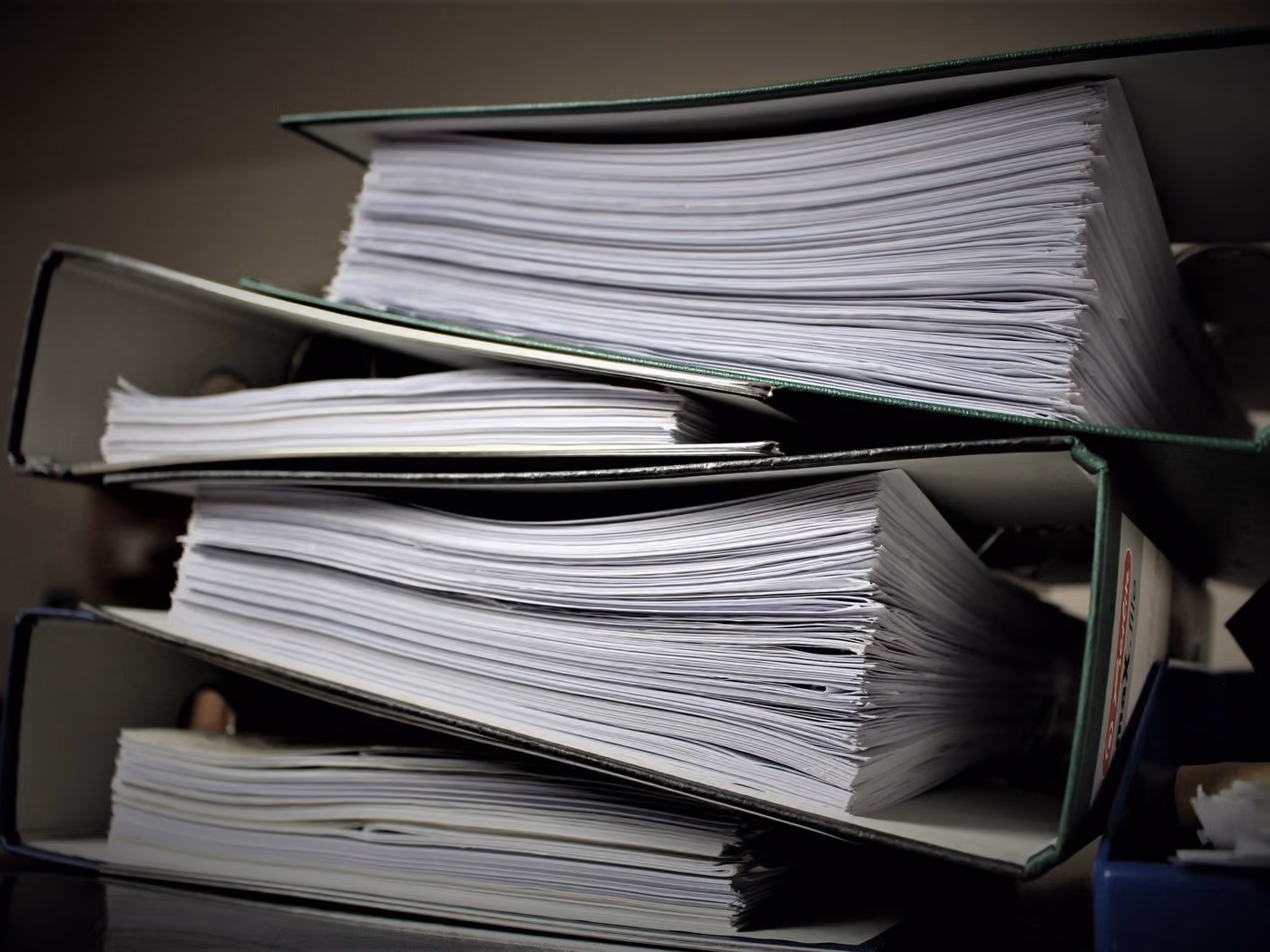 A stack of overstuffed technical binders on a shelf