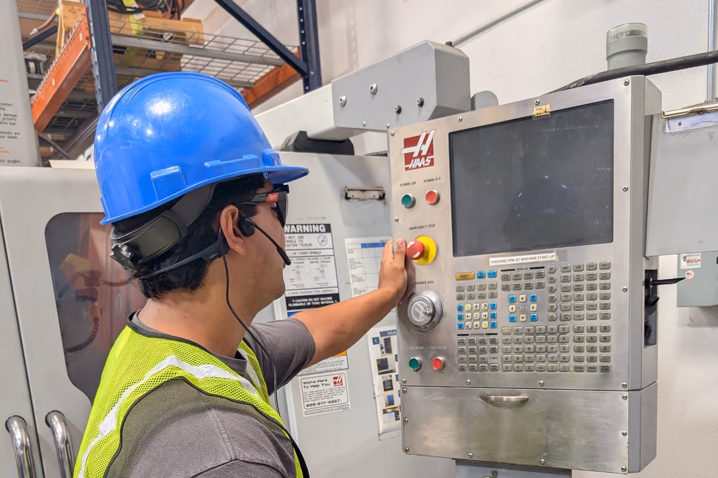 An operator wearing Amby AV glasses working one-handed at a machine control panel
