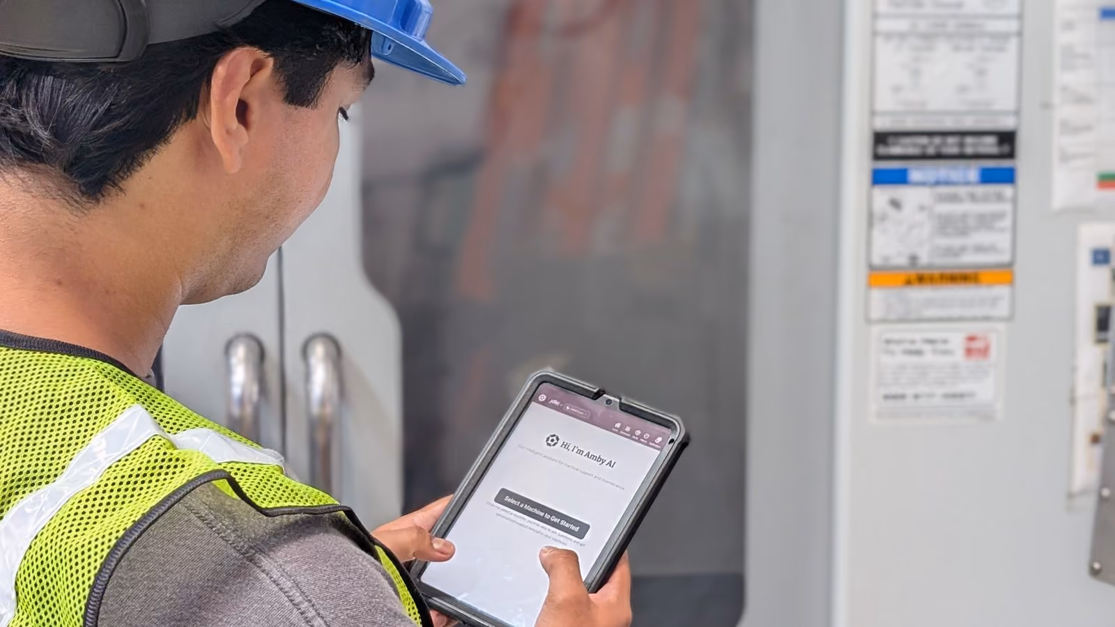 An operator at a CNC machine checking a procedure on a tablet running Amby