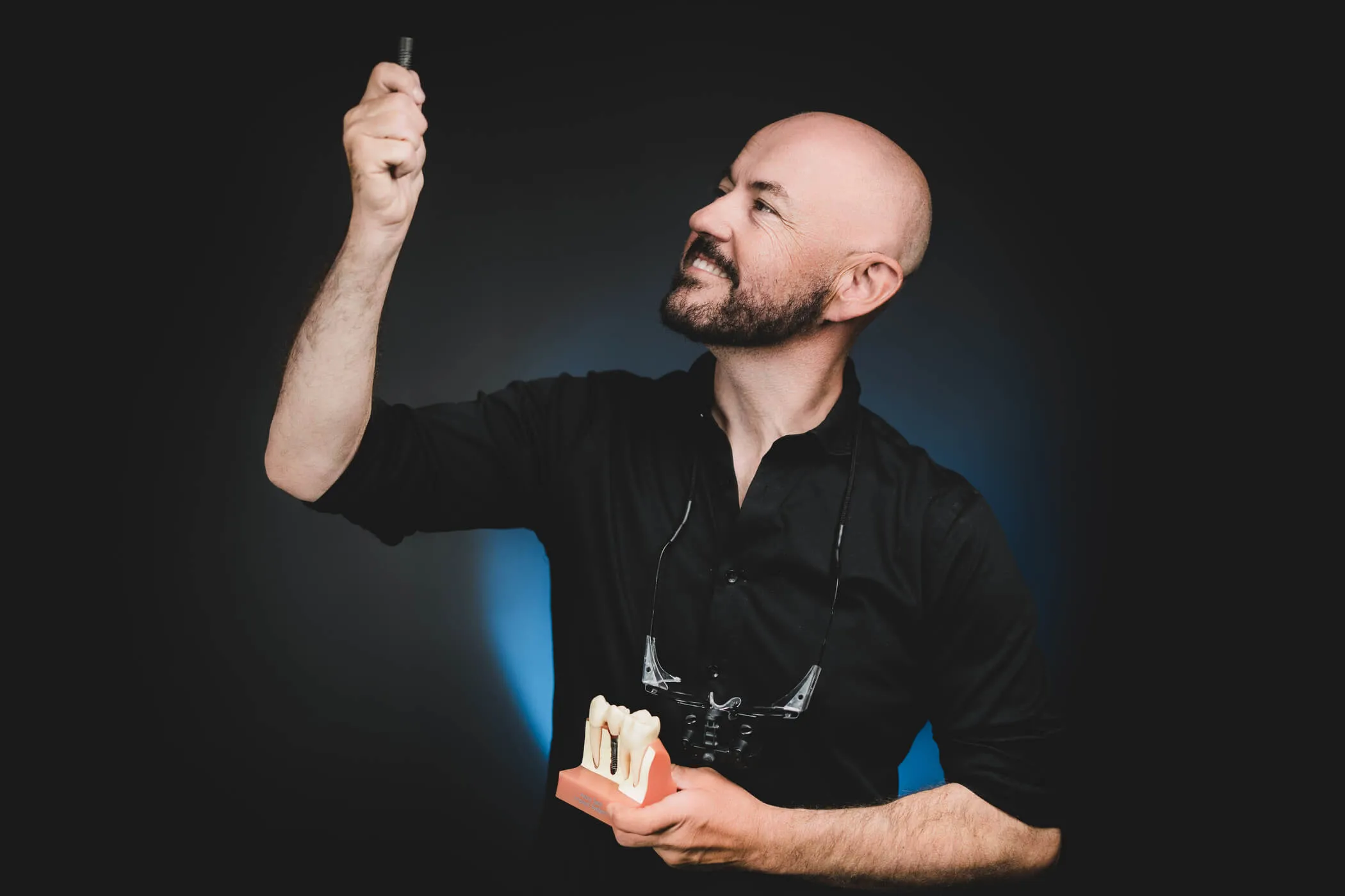 implantologia-torun-specjalista-z-modelem-zebow-i-implantem-w-reku