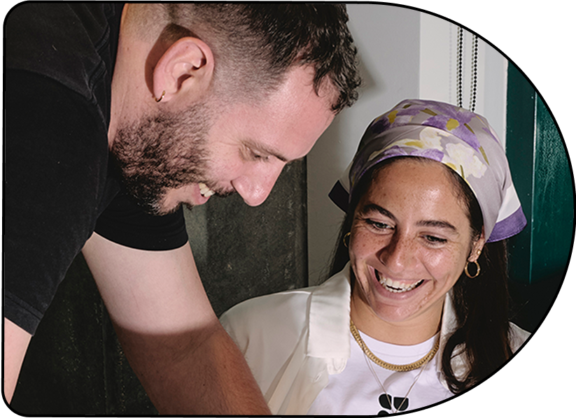 Smiling man and woman with headscarf sharing a moment together indoors.