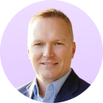 Portrait of a smiling man with short blonde hair wearing a blue suit jacket and light blue shirt.