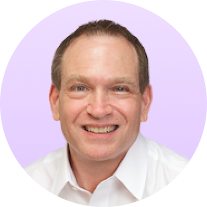 Smiling middle-aged man with short brown hair wearing a white collared shirt against a light purple background.