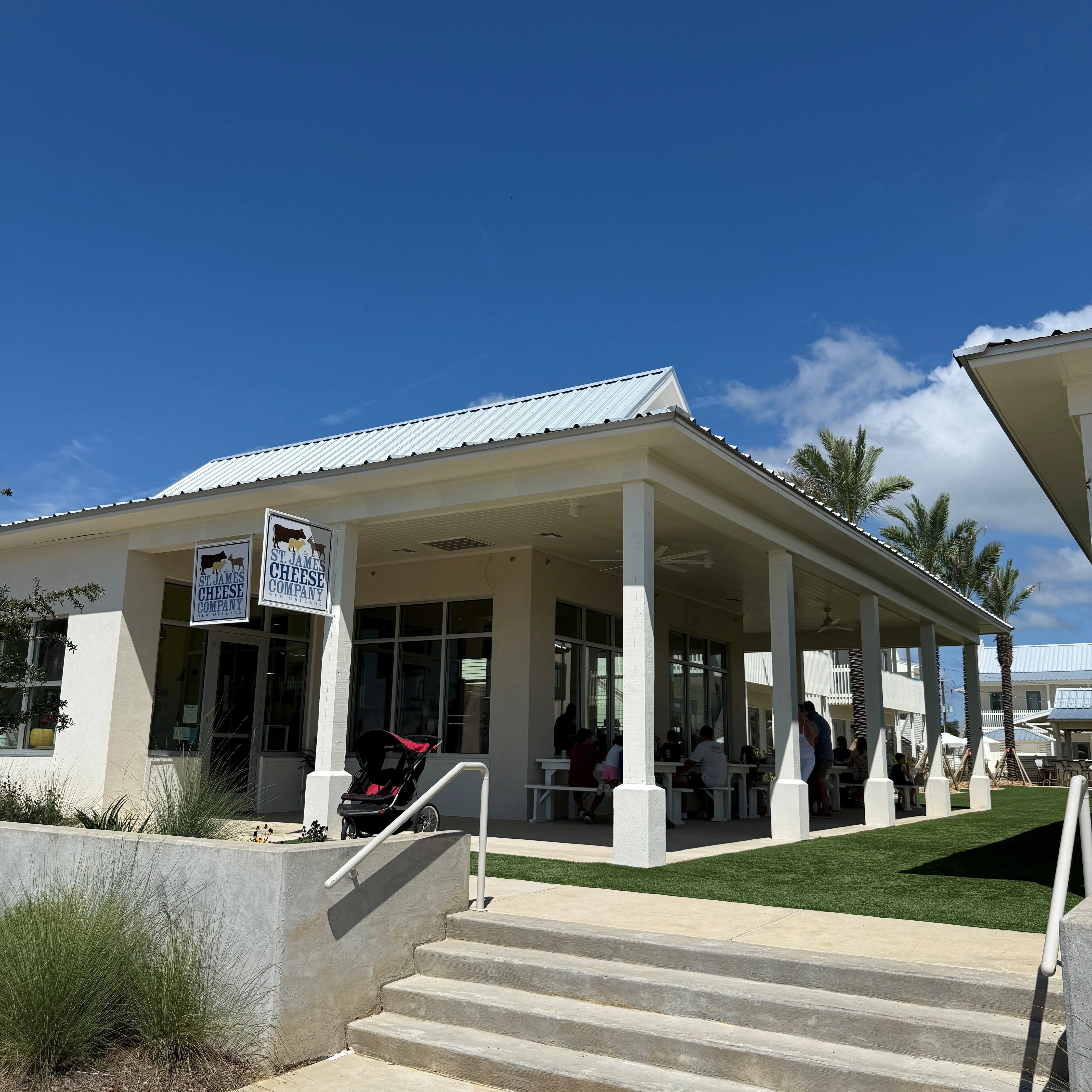 St. James Cheese Company building with outdoor seating area under a large covered porch on a sunny day.