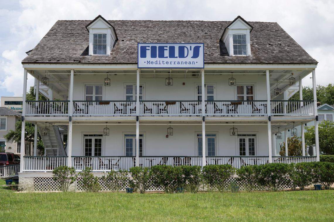 Two-story white building with porch balconies and a sign reading 'FIELD'S Mediterranean' on the roof.
