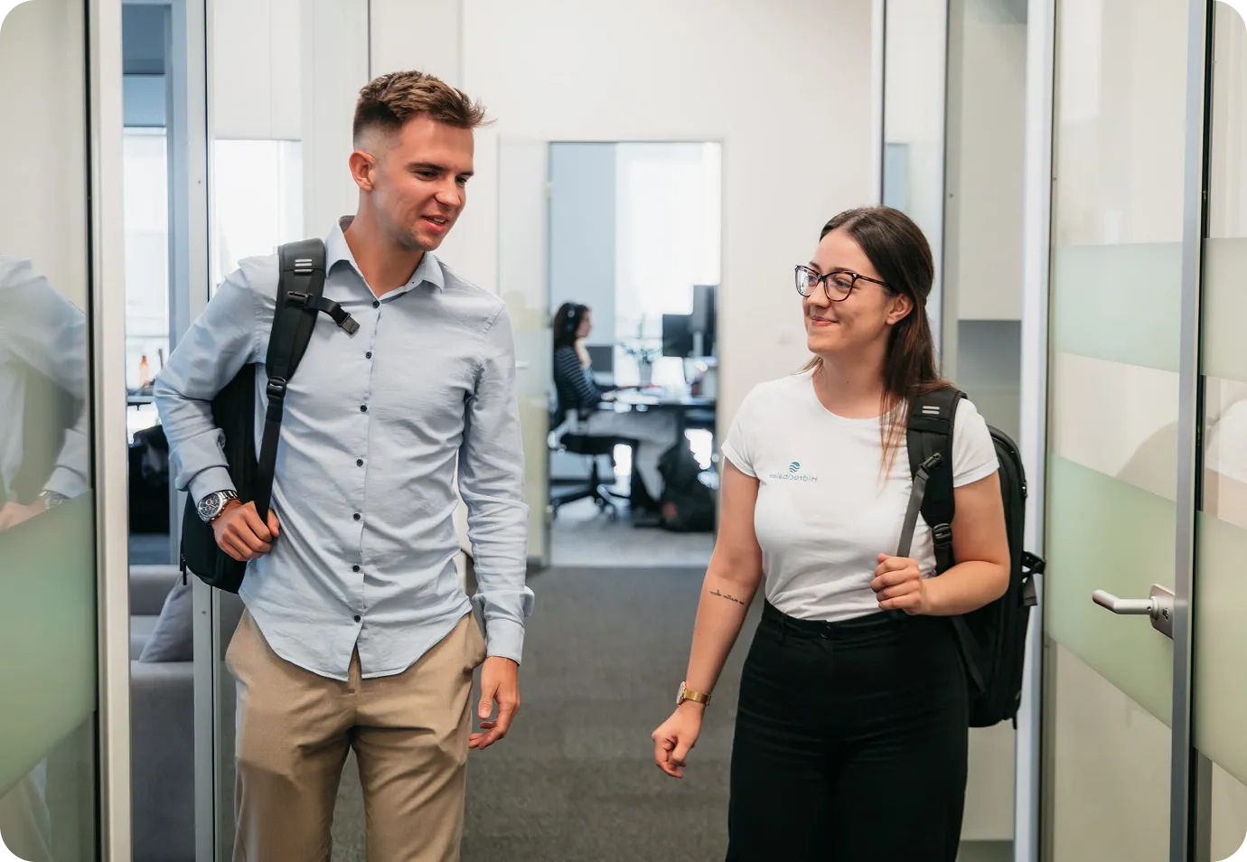 Two Hidrocibalae marine survey company employees walking and discussing projects inside a modern office environment, illustrating a collaborative workplace culture.