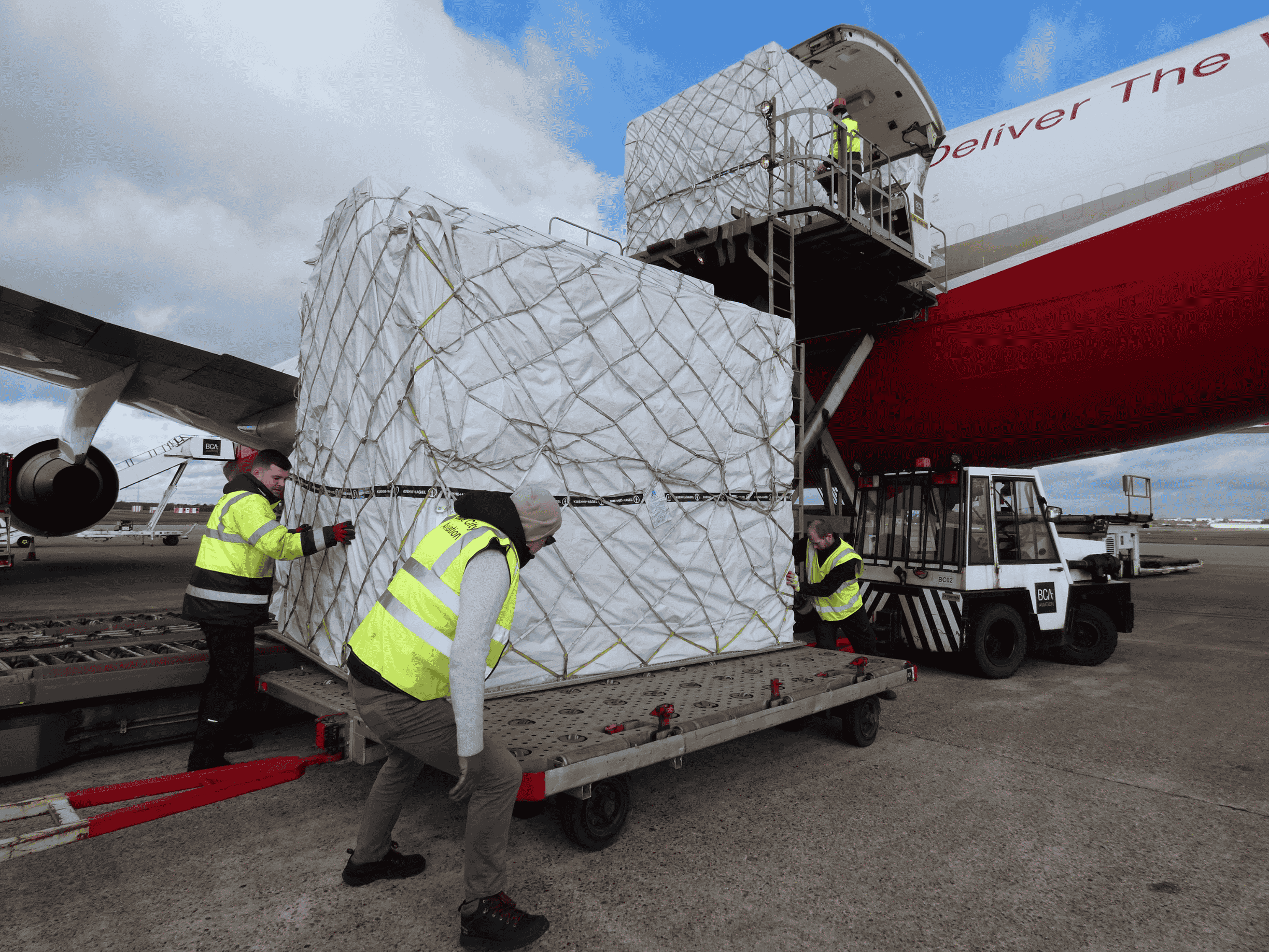 Ground crew loading palletised cargo onto a freighter aircraft