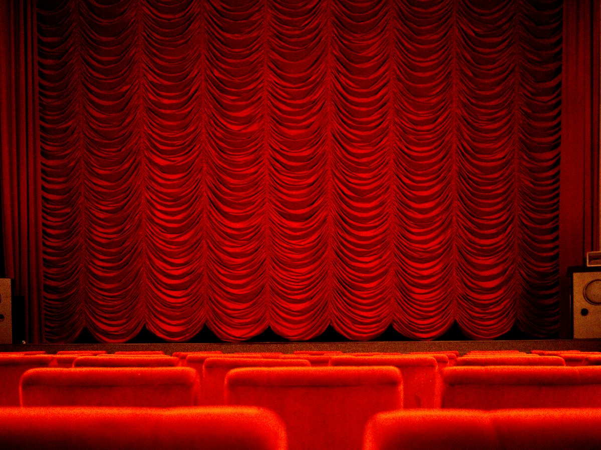 Salle de spectacle vide avec rideau rouge et fauteuils