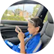 Young boy sitting in a car seat looking at a smartphone.
