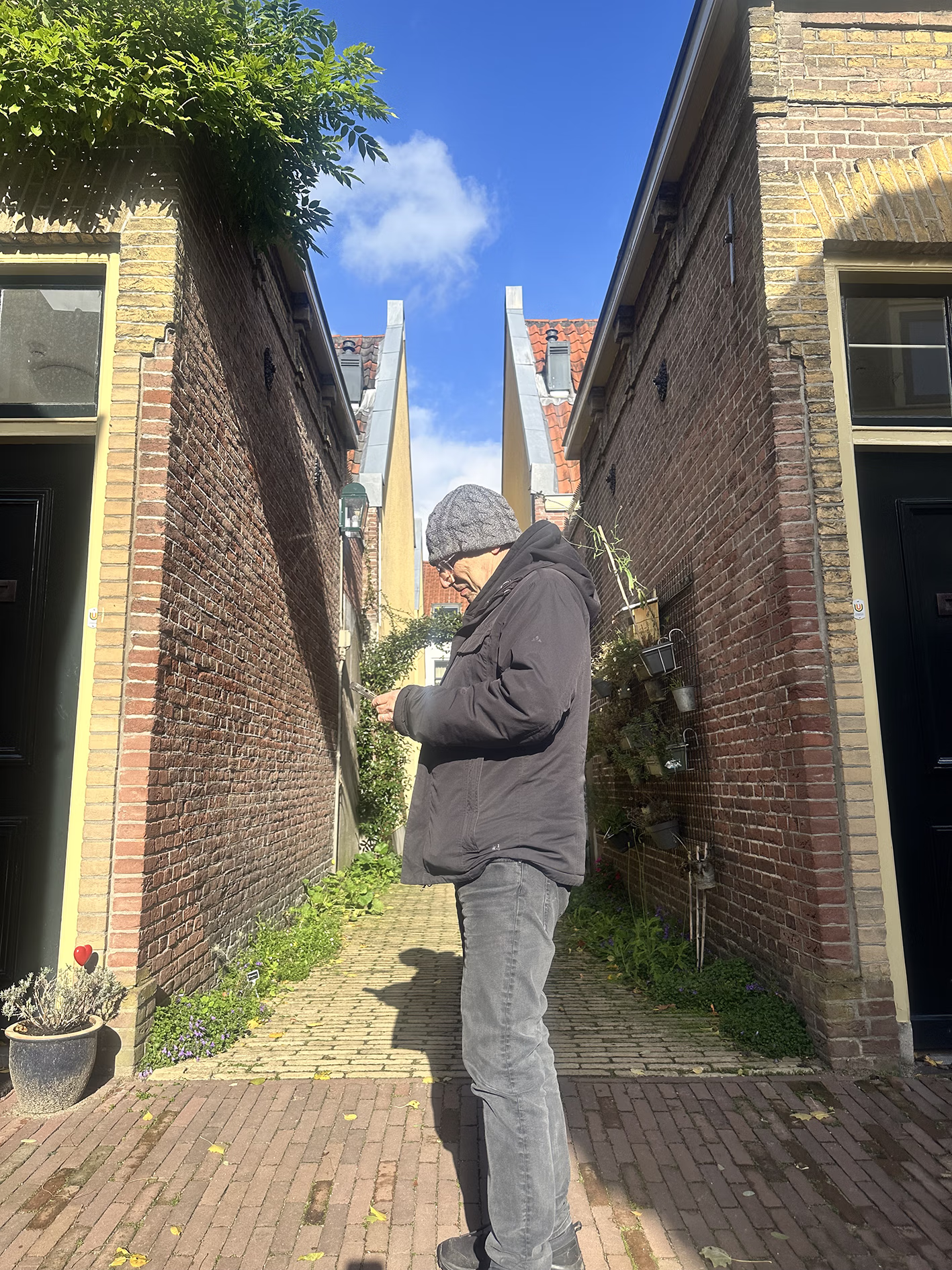 Man met muts op kijkt op zijn telefoon in een steegje in Utrecht