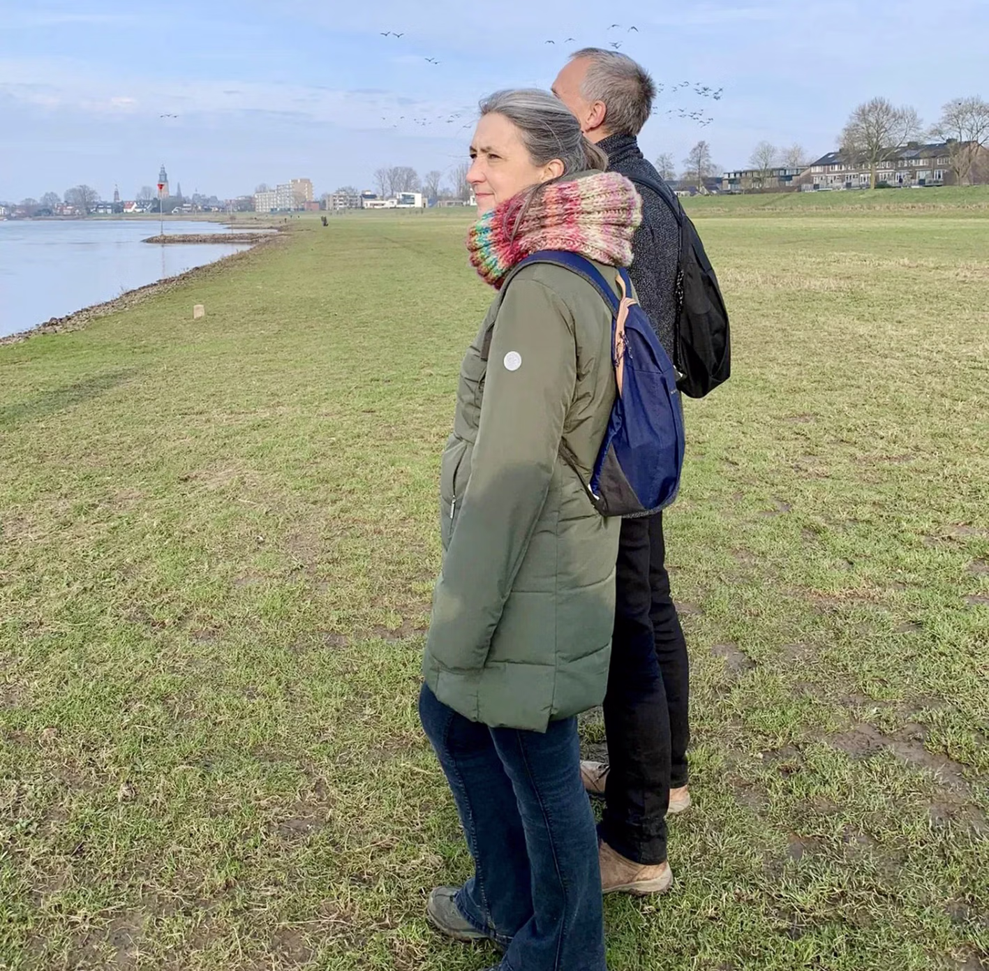 Vrouw met jas aan met man naast haar kijkt uit op een meer