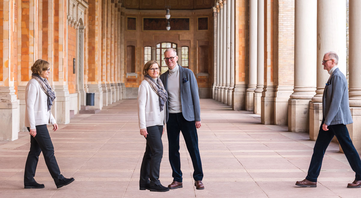 Man and woman posing in a columned walkway with multiple images of them walking from both sides.