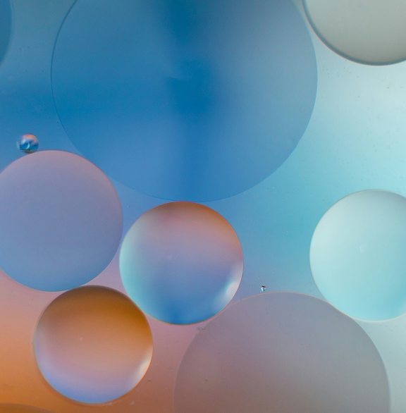 Fargerike, gjennomsiktige sirkler i ulike størrelser overlappende på en blå og oransje bakgrunn.