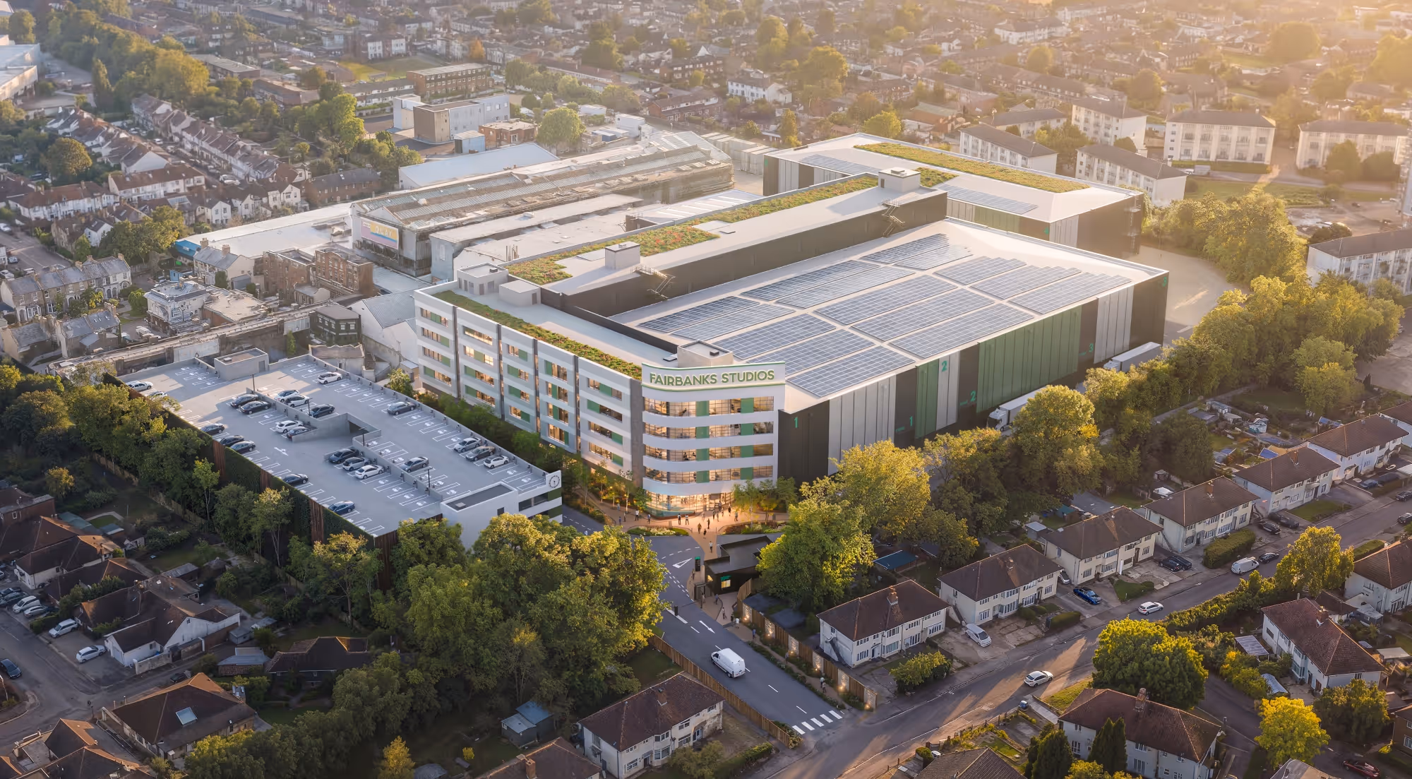Aerial view of Fairbanks Studios surrounded by residential buildings and greenery during sunset.