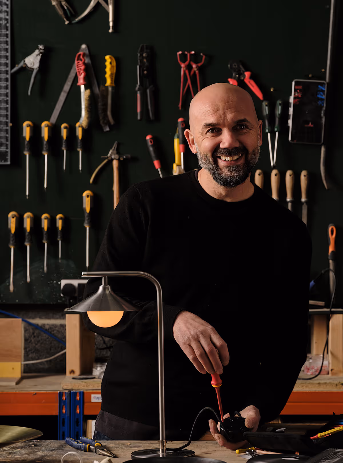 Bujar assembling a light at a workshop bench.