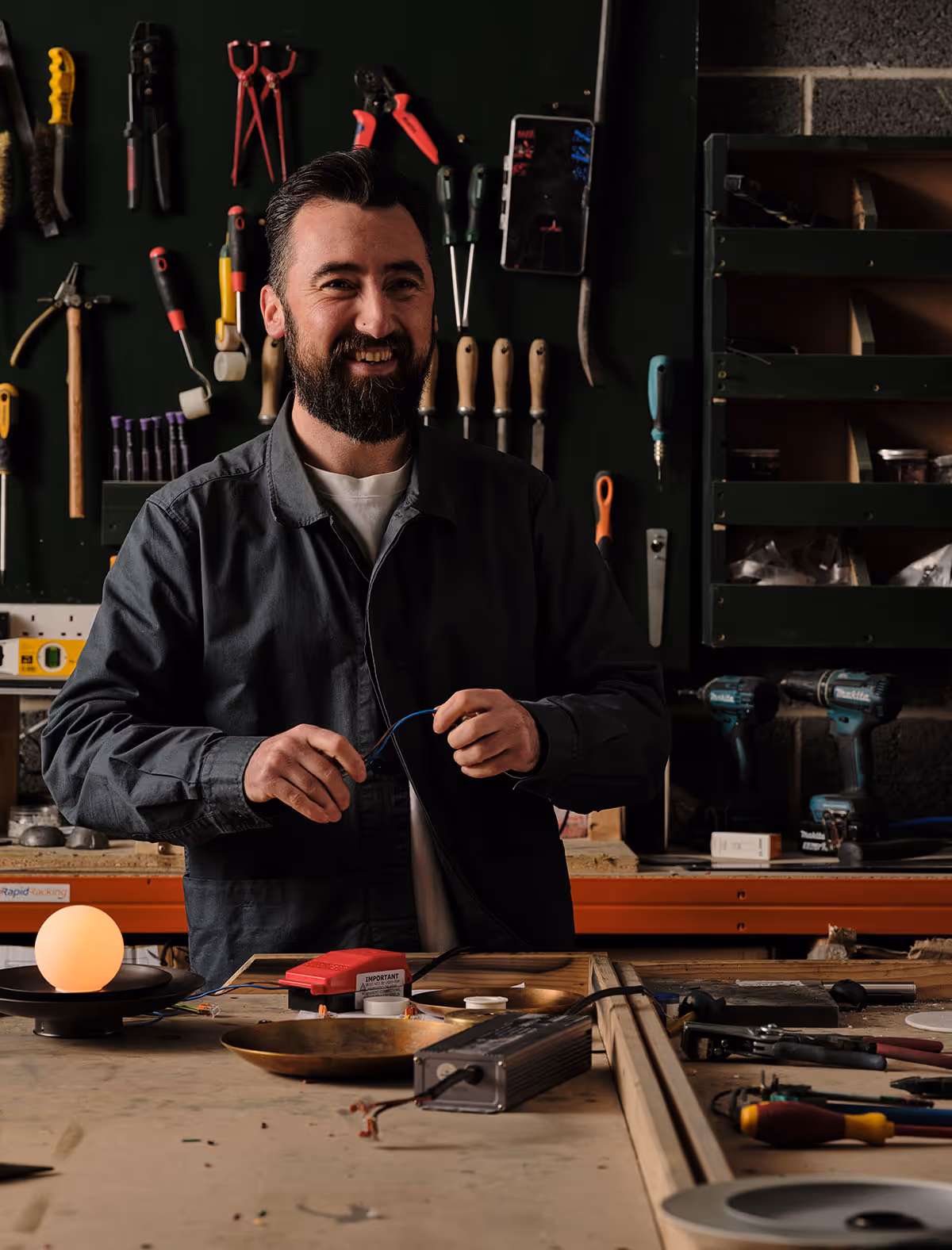 Darren smiling at a workshop bench with lighting components.