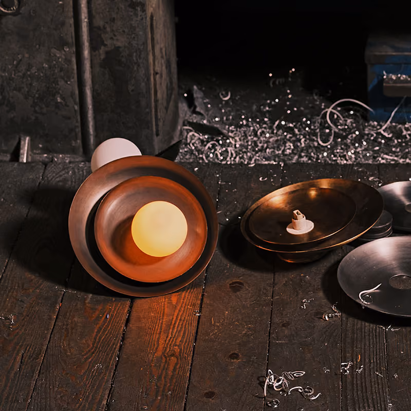 Glowing Spin Drift light and separate metal shades on a workshop bench.